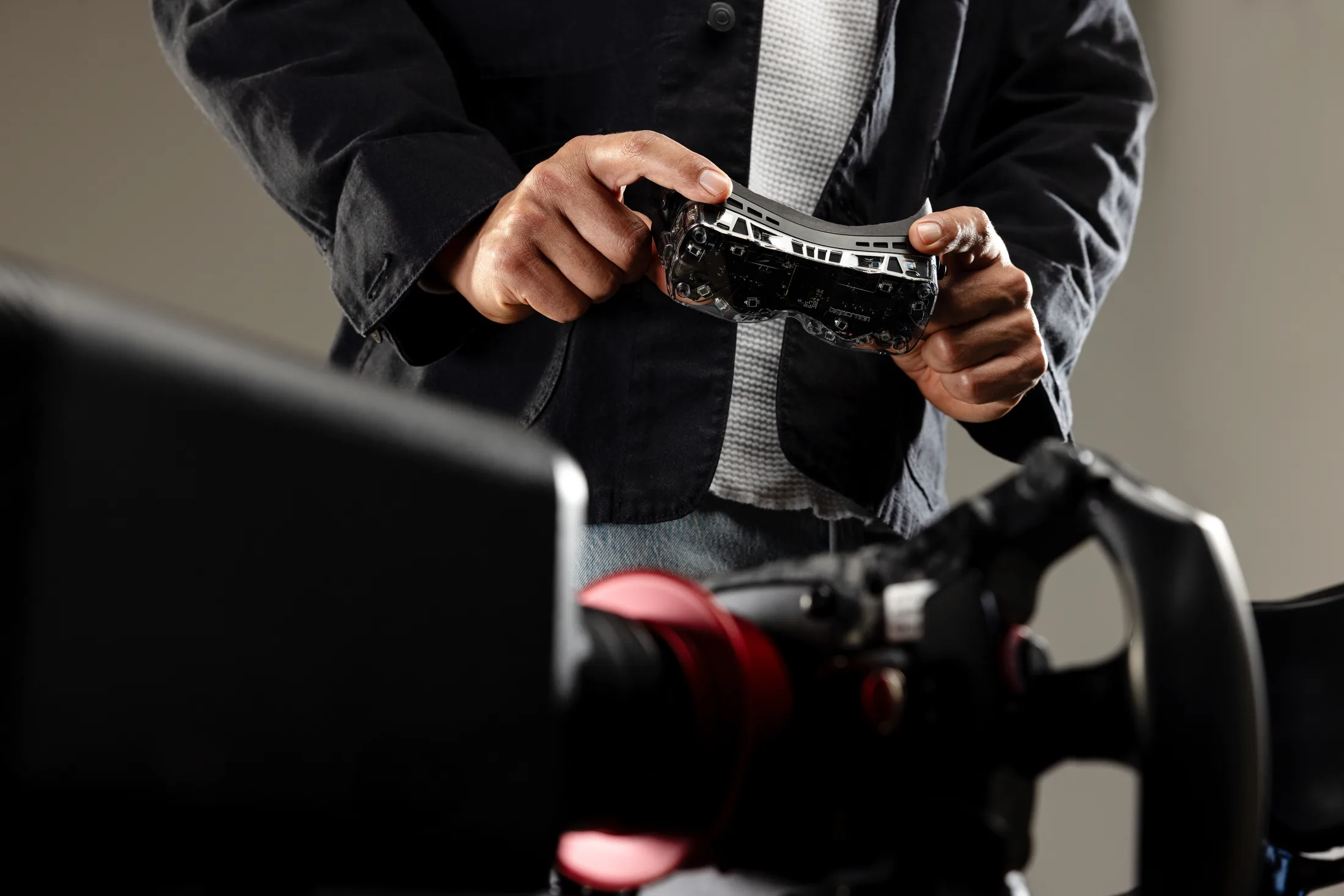 Driver holding a Bigscreen Beyond 2 headset at a racing simulator