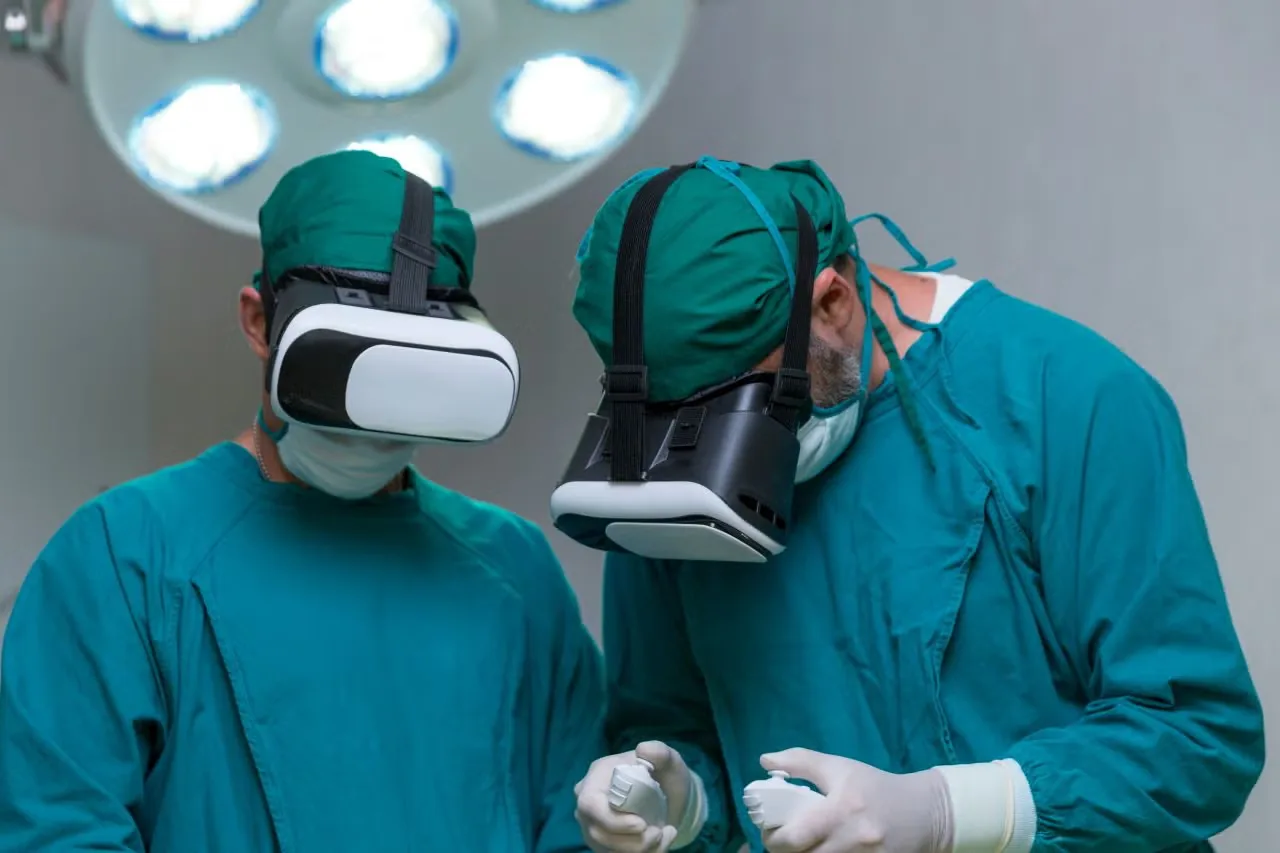 Two surgeons wearing VR headsets under an operating lamp